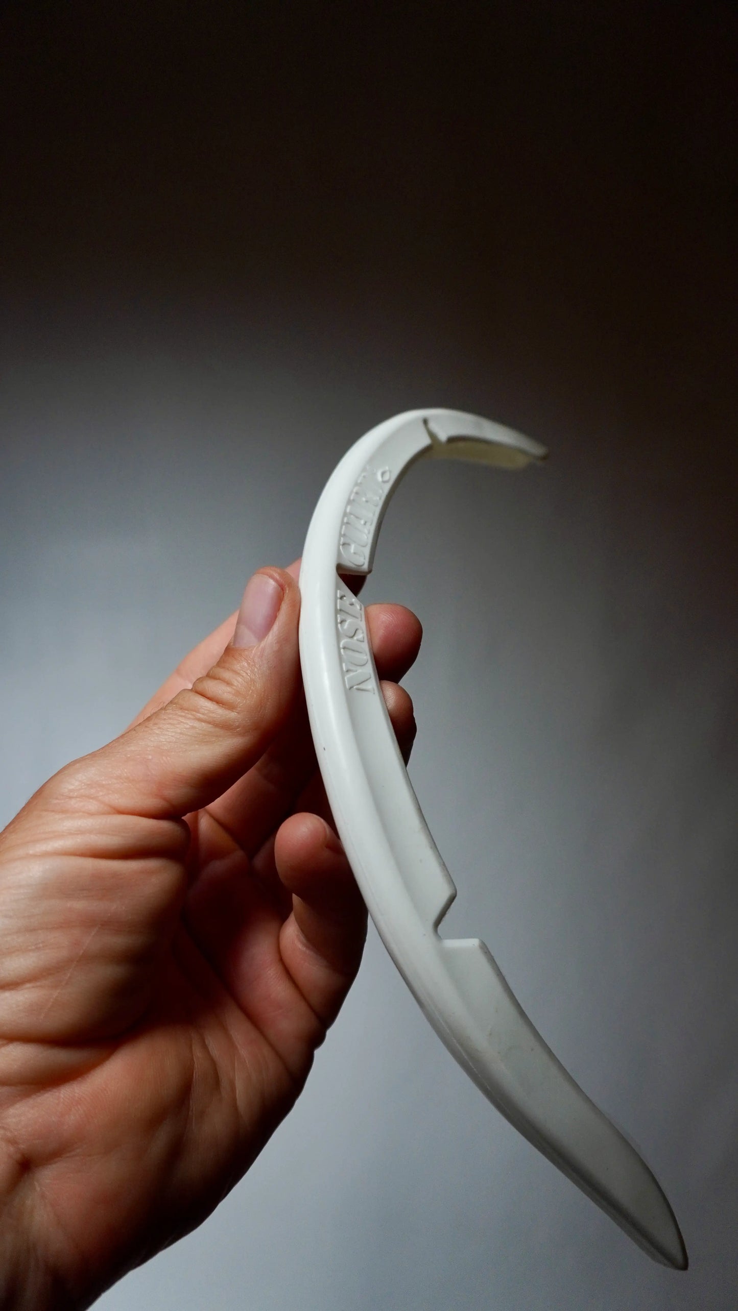 SurfCo Hawaii Fun Shape Nose Guard v bílé barvě – flexibilní ochrana špičky surfboardu, detailní pohled v ruce.