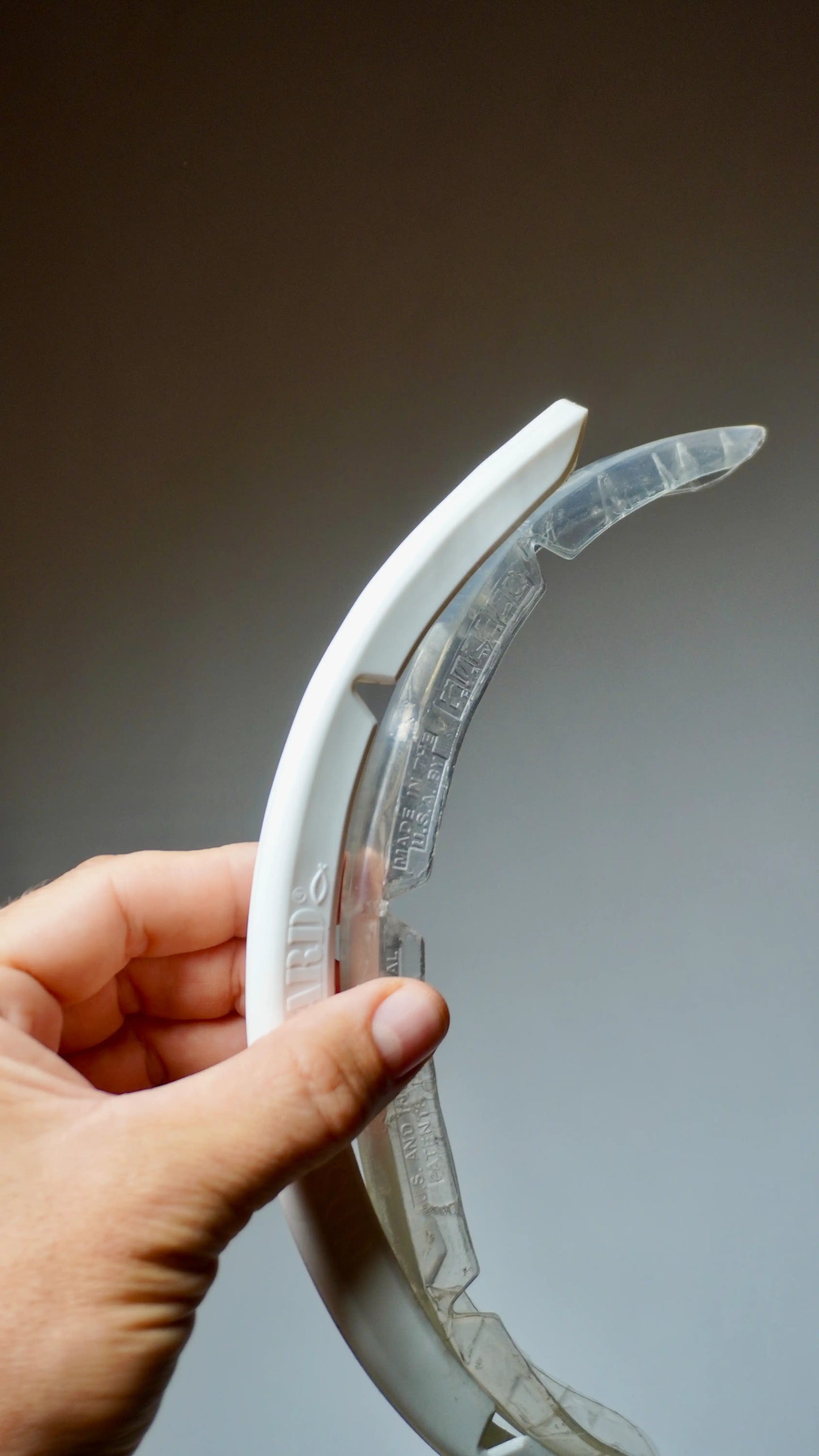 SurfCo Hawaii Fun Shape Nose Guard – bílý a čirý chránič špičky surfboardu, držené v ruce, flexibilní zakřivený tvar.