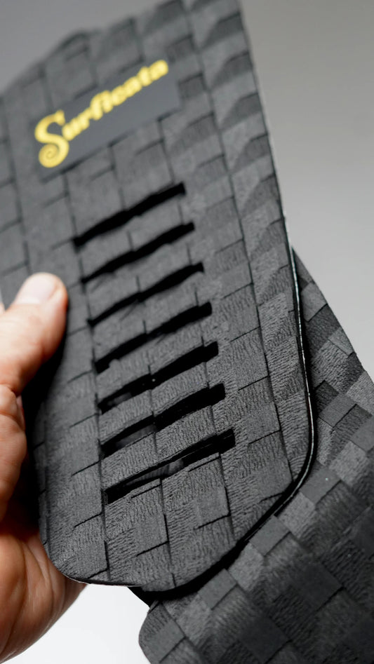Detail středového dílu černého tail padu Surficata Blackout s podélnými výřezy a EVA strukturou.