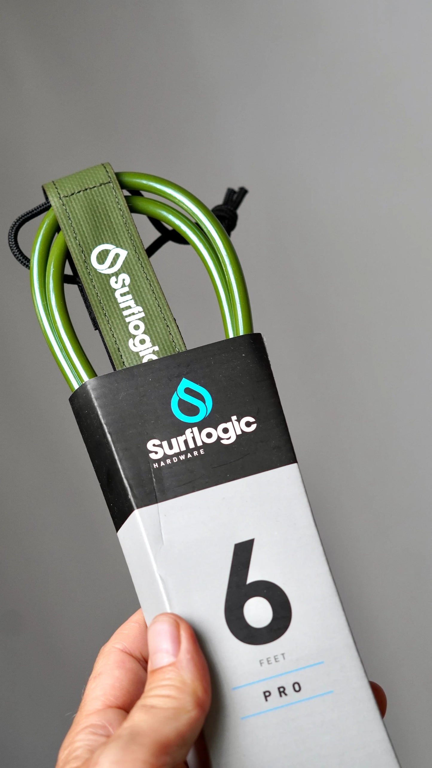 Olive green Surflogic leash in packaging held in hand