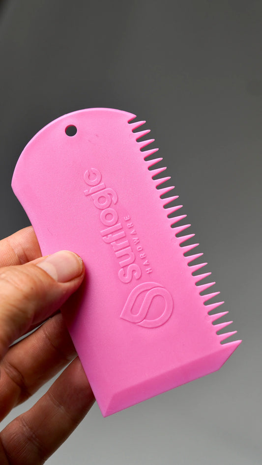 Růžový Surflogic Wax Comb – škrabka a hřeben na surfový vosk v ruce