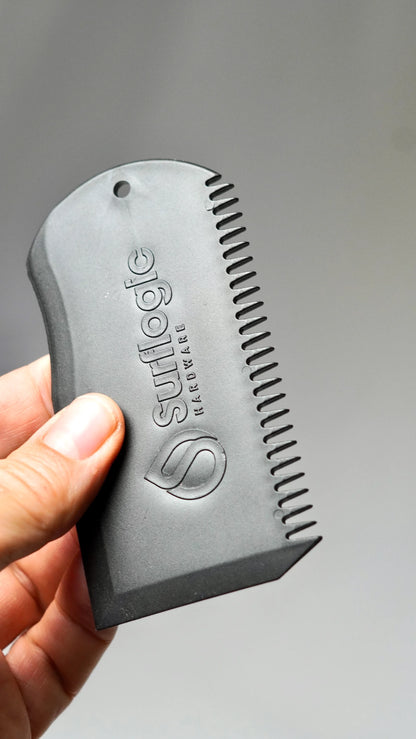 černý Surflogic Wax Comb v ruce – škrabka a hřeben na surfový vosk