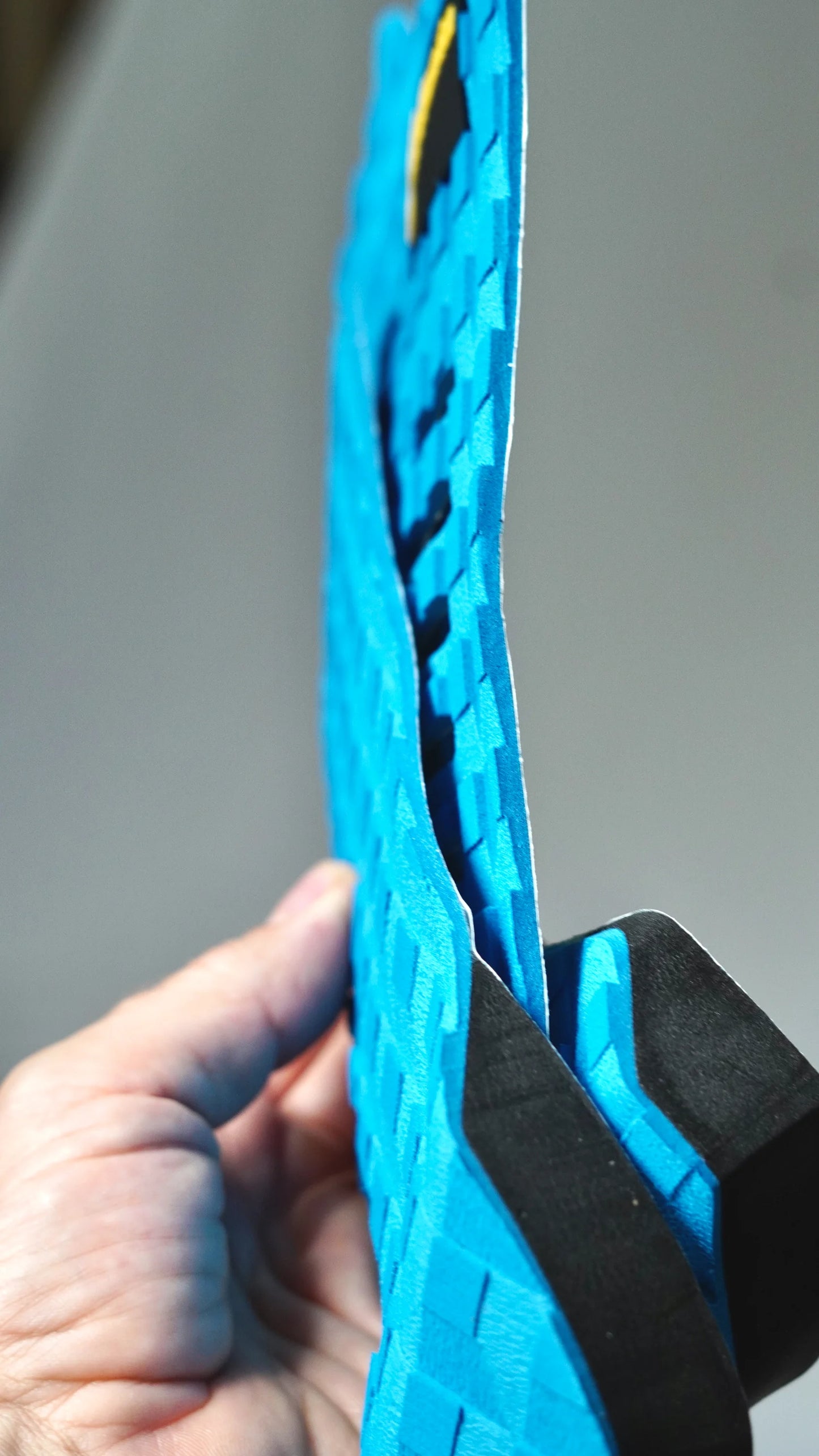 Boční pohled na modrý tail pad Surficata Electric Blue, s tenkým EVA profilem a černou spodní vrstvou.
