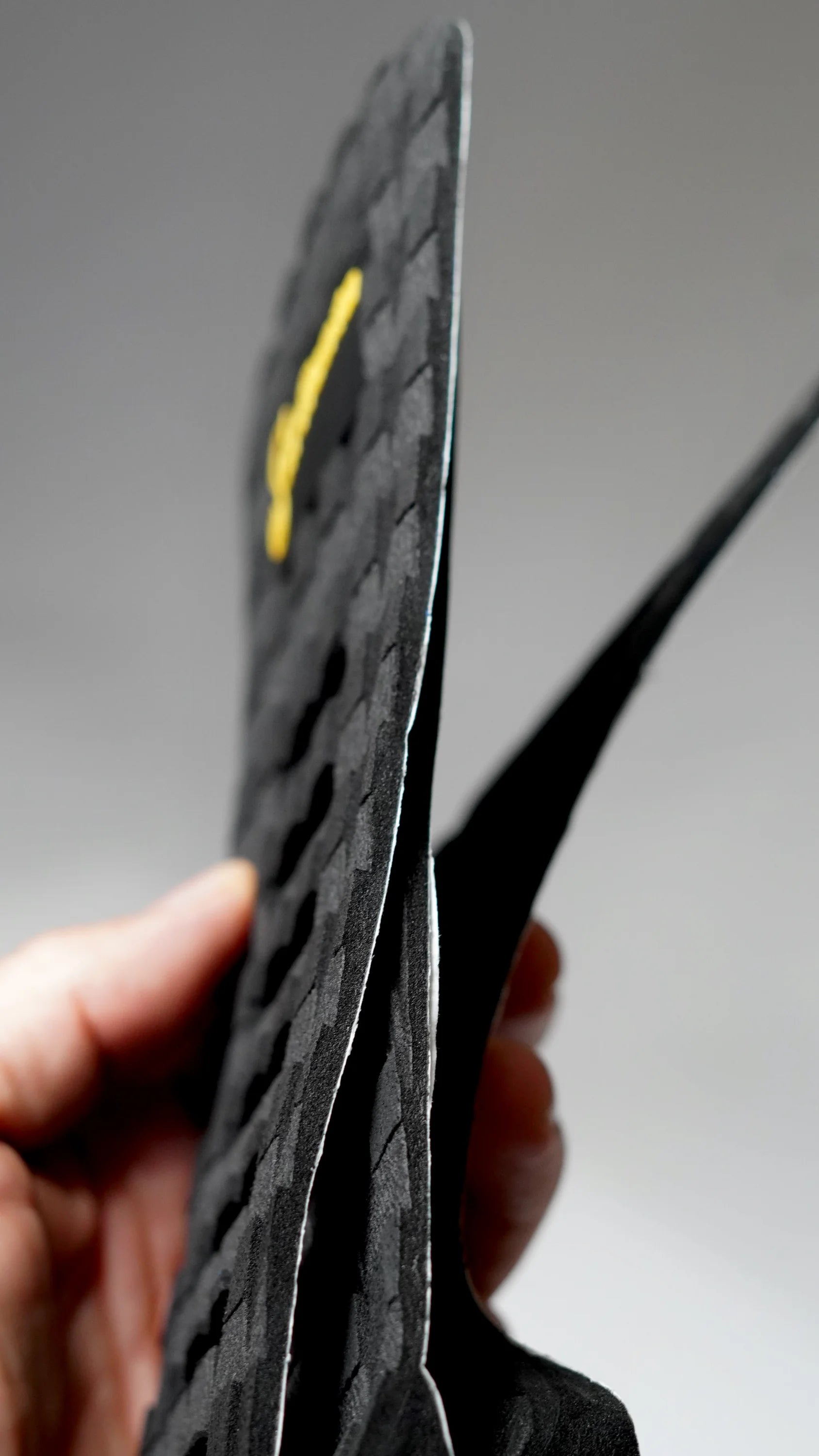 Boční pohled na černý tail pad Surficata Blackout s tenkým EVA profilem.